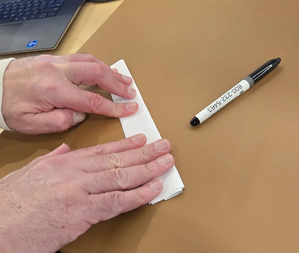 Hands pressing paper tube flat