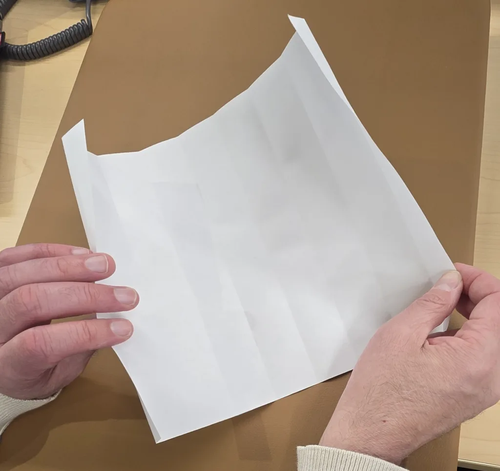 hands open paper tube that makes lines spaced on the paper