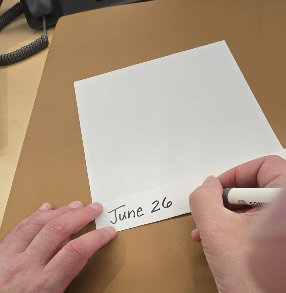Person writing date on the paper