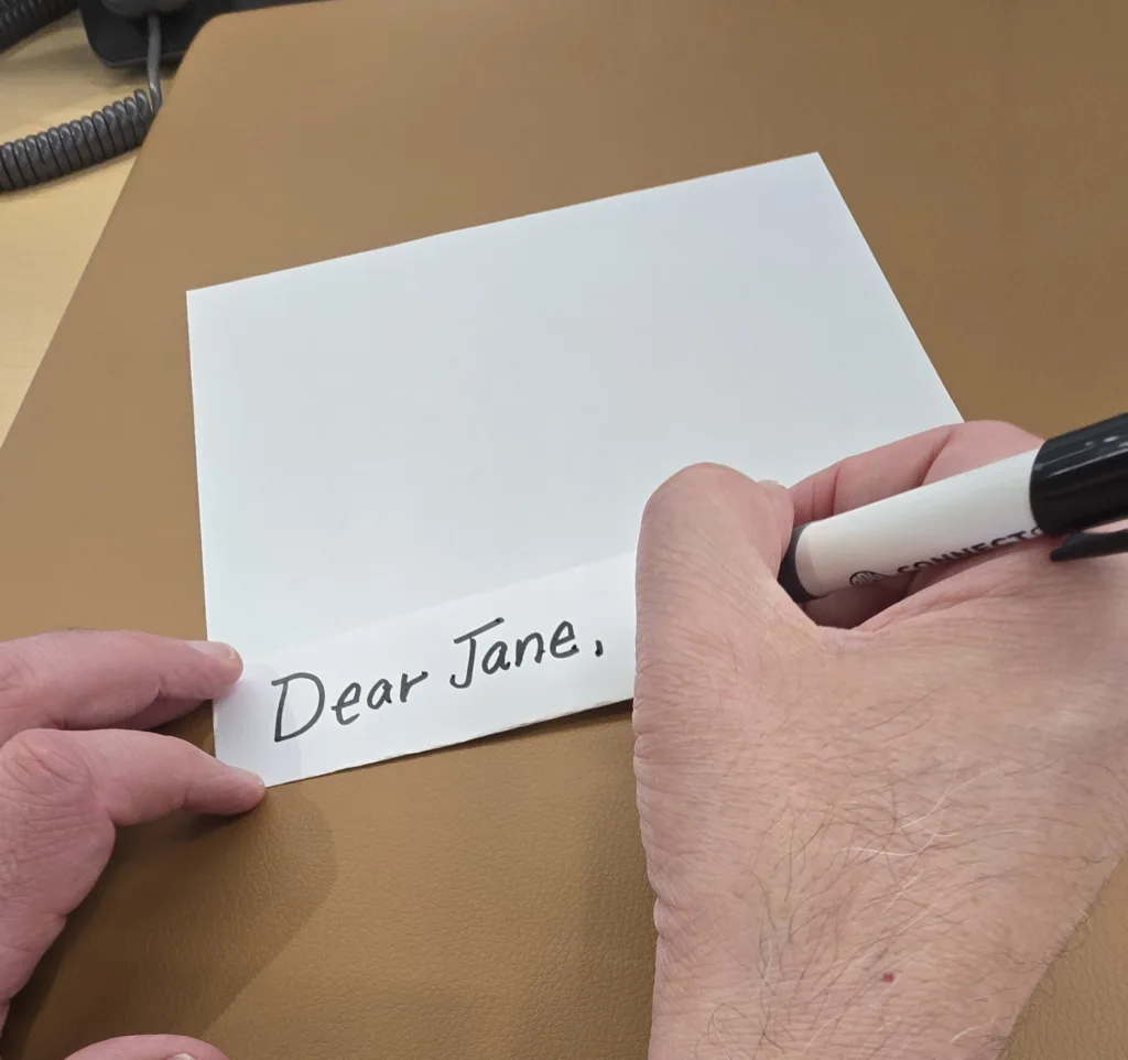 Person writes "dear jane" on the other fold of paper.