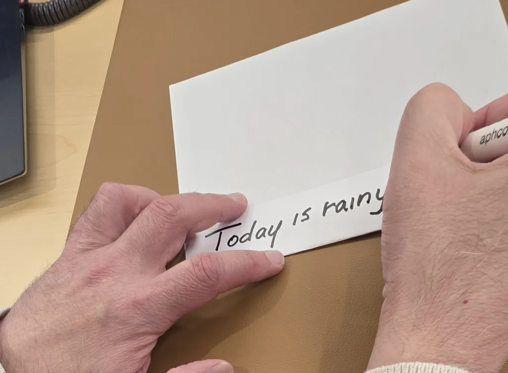 Person writes "today is rainy" on the paper fold. 