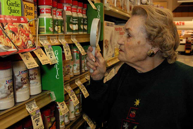Woman using magnifier to look at canned goods in grocery store