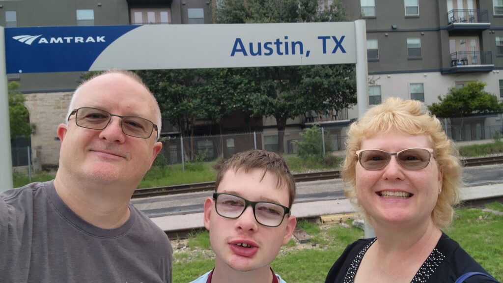 Parents standing with their teen in front of an Austin TX sign
