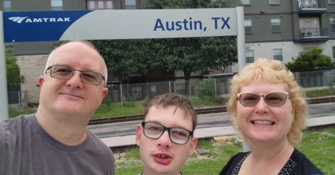 Parents standing with their teen in front of an Austin TX sign