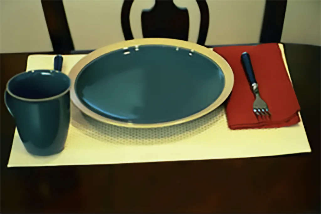 dark colored plate on light colored plate with red napkin in contrast to the yellow placemat