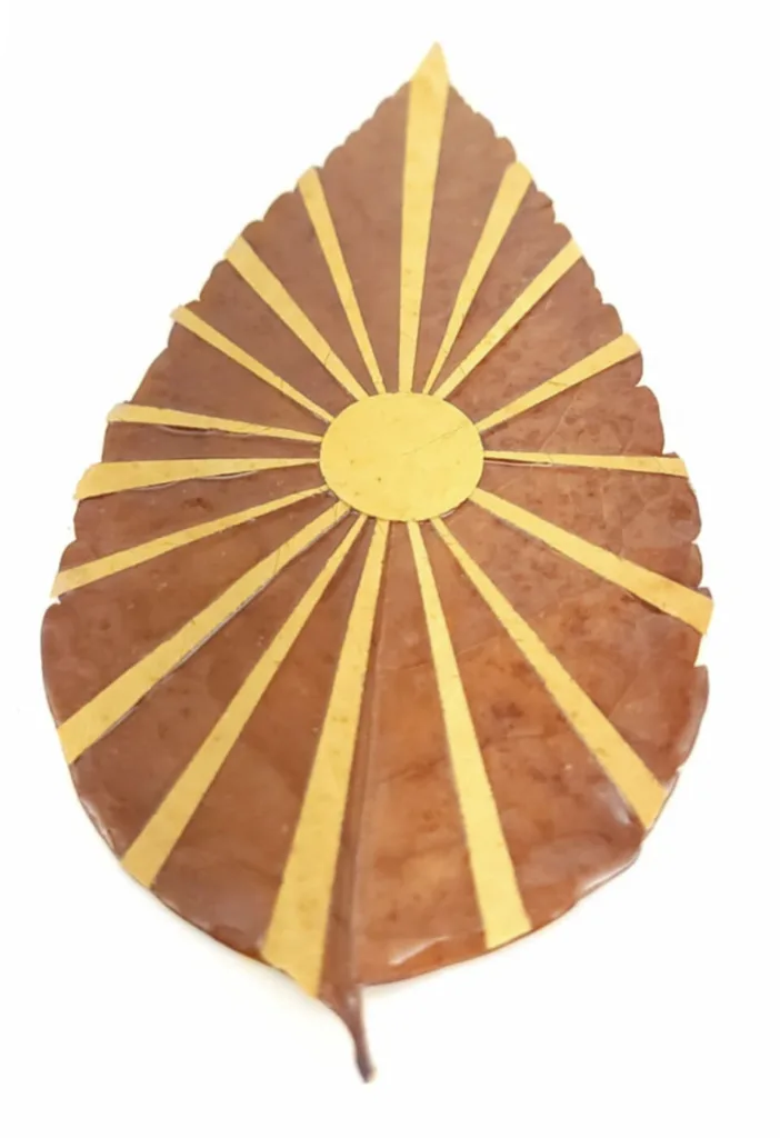 large brown leaf with glued-on yellow circle in the center with lines coming from the circle reaching the outer edges of the leaf form a tactile sunburst 