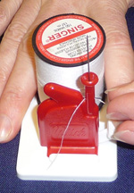 Pinch the metal foot and the thread loop between your thumb and index finger and pull your fingers away from the threading unit. You will now be holding the thread between your fingers.