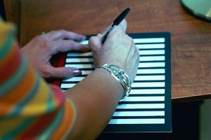 closeup of person using a writing guide and a bold black marker to write