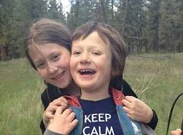 Siblings standing outside with boy holding a white cane wearing a "Keep Calm - it's just a cane" T shirt.