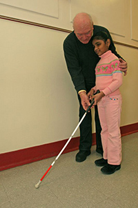 An orientation and mobility instructor working with a school-aged girl