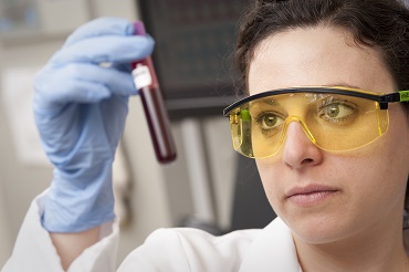 lab tech examines vial of blood image credit to National Eye Institute
