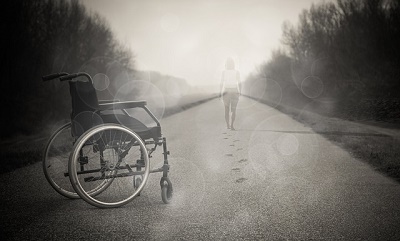 empty wheelchair in street with woman walking in distance