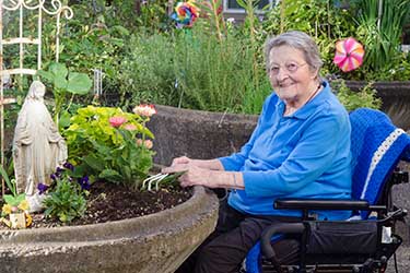A woman in a wheelchair outside working in a raised garden