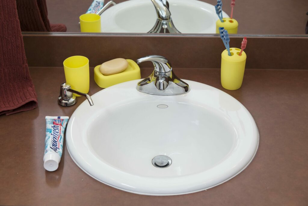 dark colored bathroom counter with bright yellow contrasting toothbrush holder, soap tray, and cup