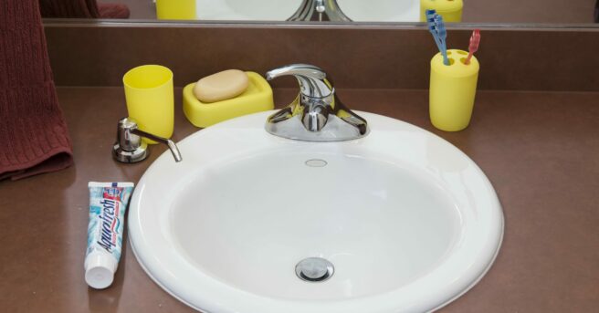 dark colored bathroom counter with bright yellow contrasting toothbrush holder, soap tray, and cup