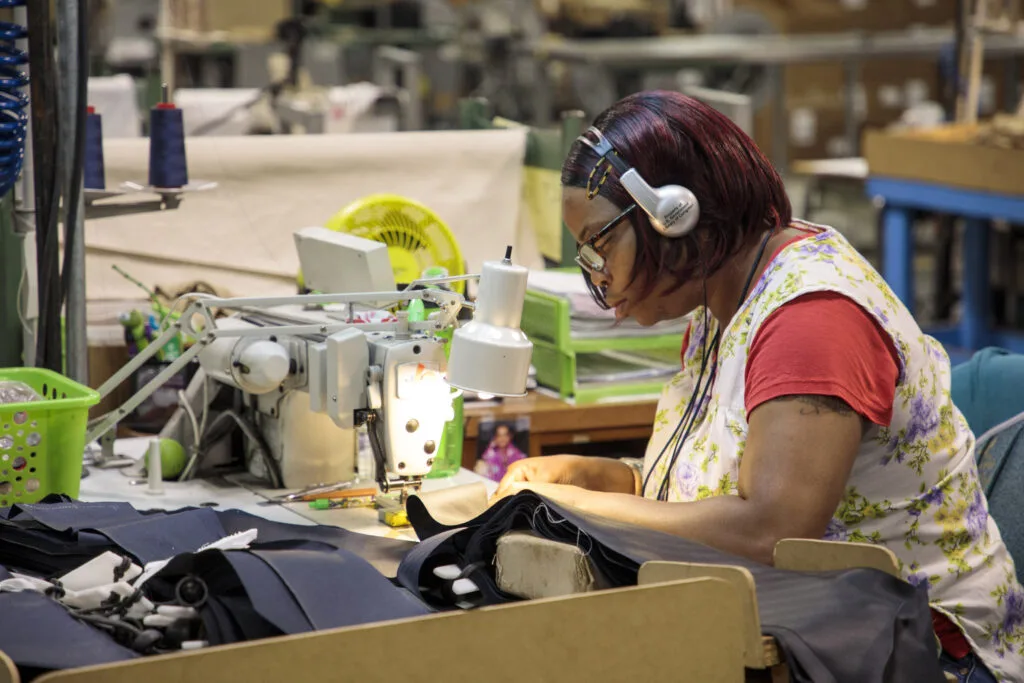 Woman with glasses and headphones working at a sewing table