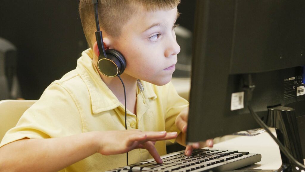 Estudiante masculino utilizando una computadora de escritorio y un teclado