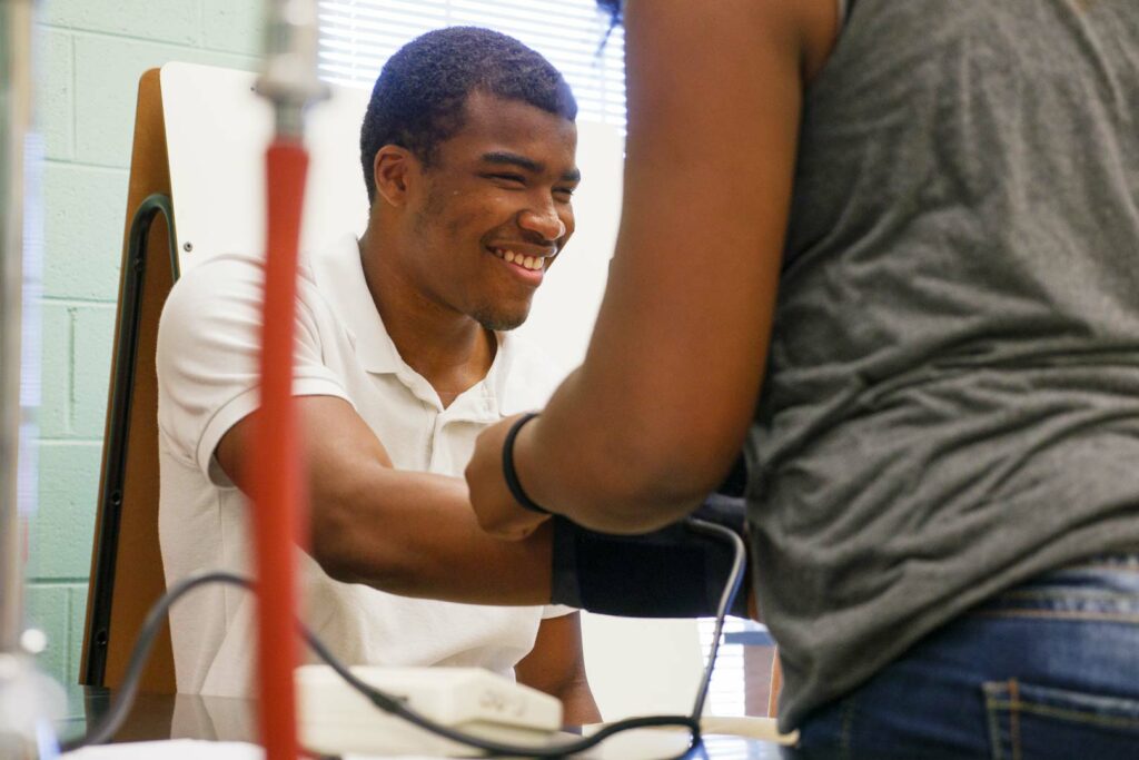 A student exploring a blood pressure cuff on his arm.
