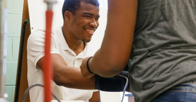 A student exploring a blood pressure cuff on his arm.
