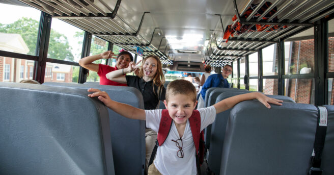 Elementary students on a bus walking between seats.