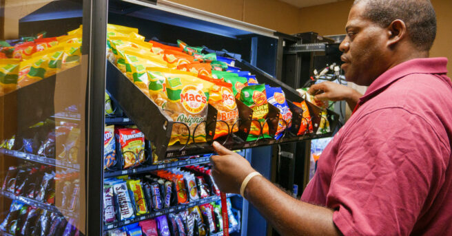 A man stocking a vending machine.