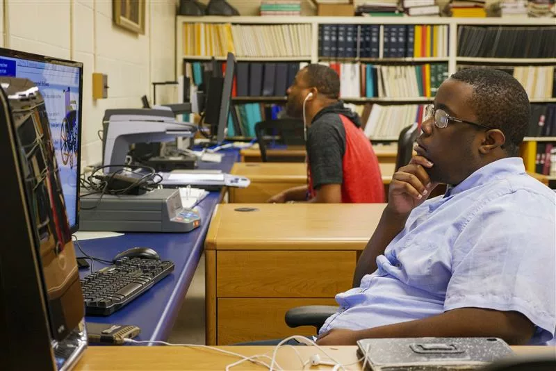 man sitting at desk looking at computer with magnification