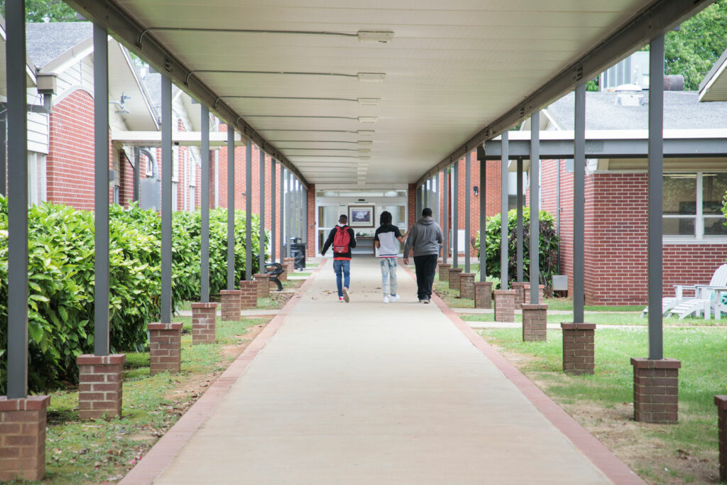 A group of three students walking into a school.