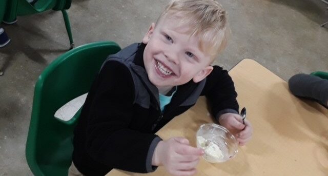 Fair-Skinned boy sitting at a table and smiling