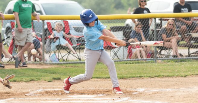 Youth in unform swinging a baseball bat