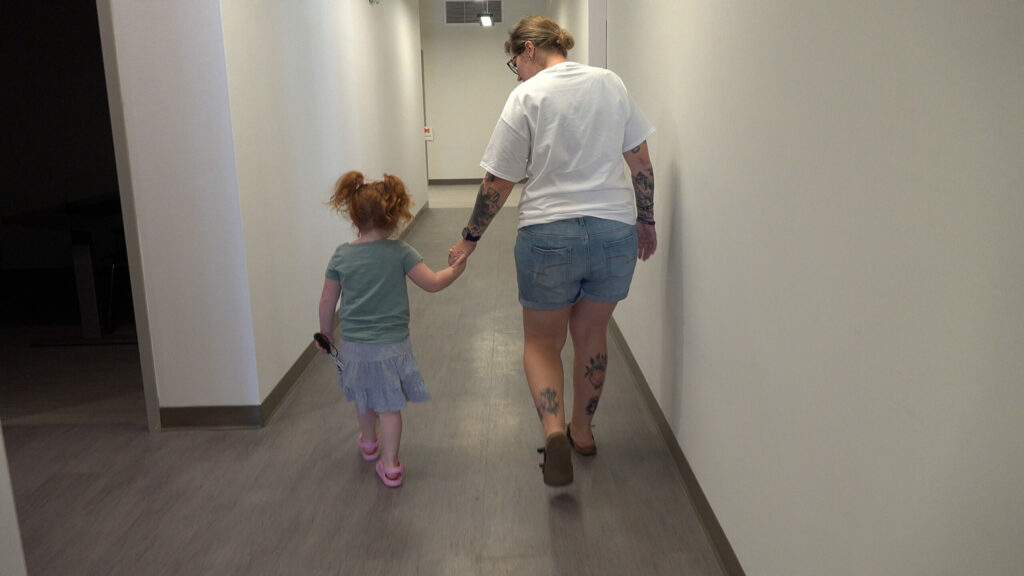 A preschooler walking in the hall with a cane and her Orientation and Mobility instructor.