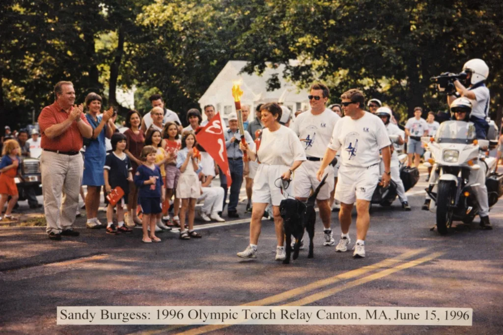 Sandra Burgess walks with her guide dog while carrying the Olympic torch for the 1996 Summer Olympics.