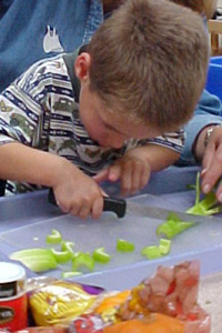 young boy cutting celery with a sharp knife