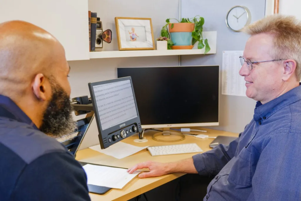 two men consulting with each other on computer