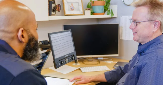 two men consulting with each other on computer