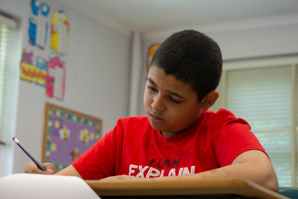 A student sitting at a desk writing on paper.