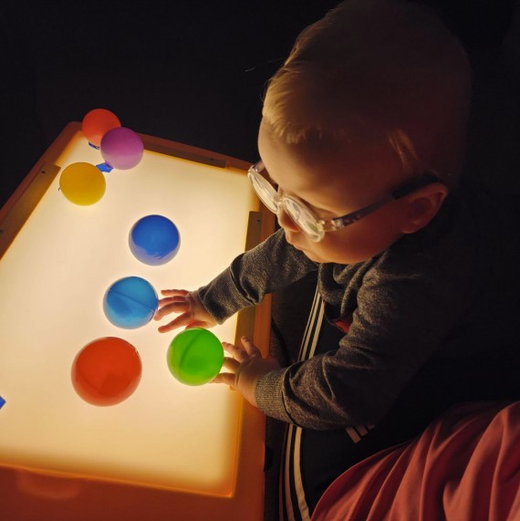 Dominic is playing with a light box. He has colorful balls stuck on it.