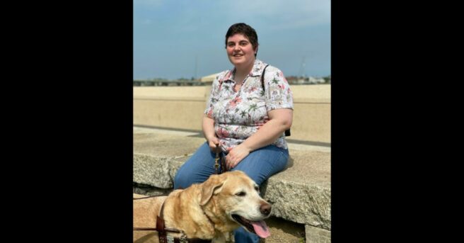 Individual sits outside with backpack and a dog guide