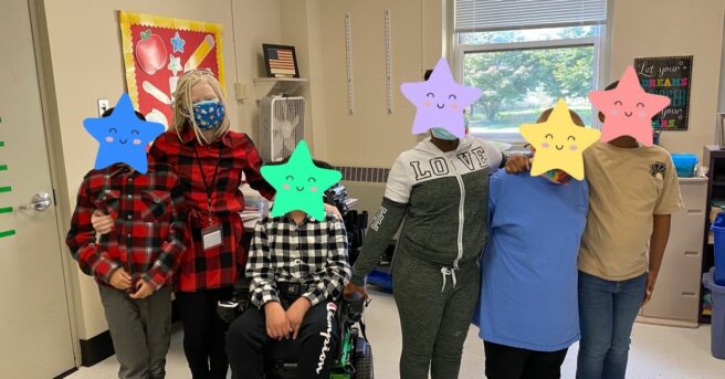 A young teacher stands with her upper middle school students; the students' heads are covered by stars for privacy.