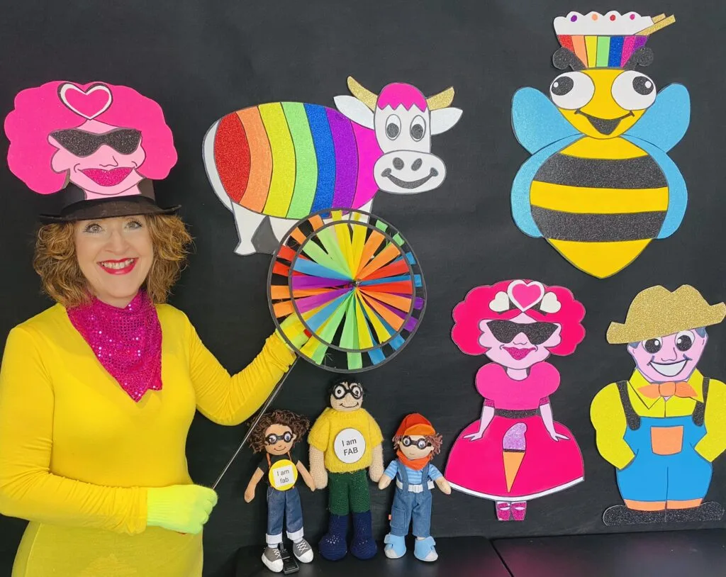 Gwyn holds a colorful round object with her many characters including a large bee, bull, farmer and woman.