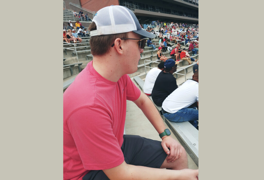 author wearing a brimmed hat and sunglasses at a sporting event
