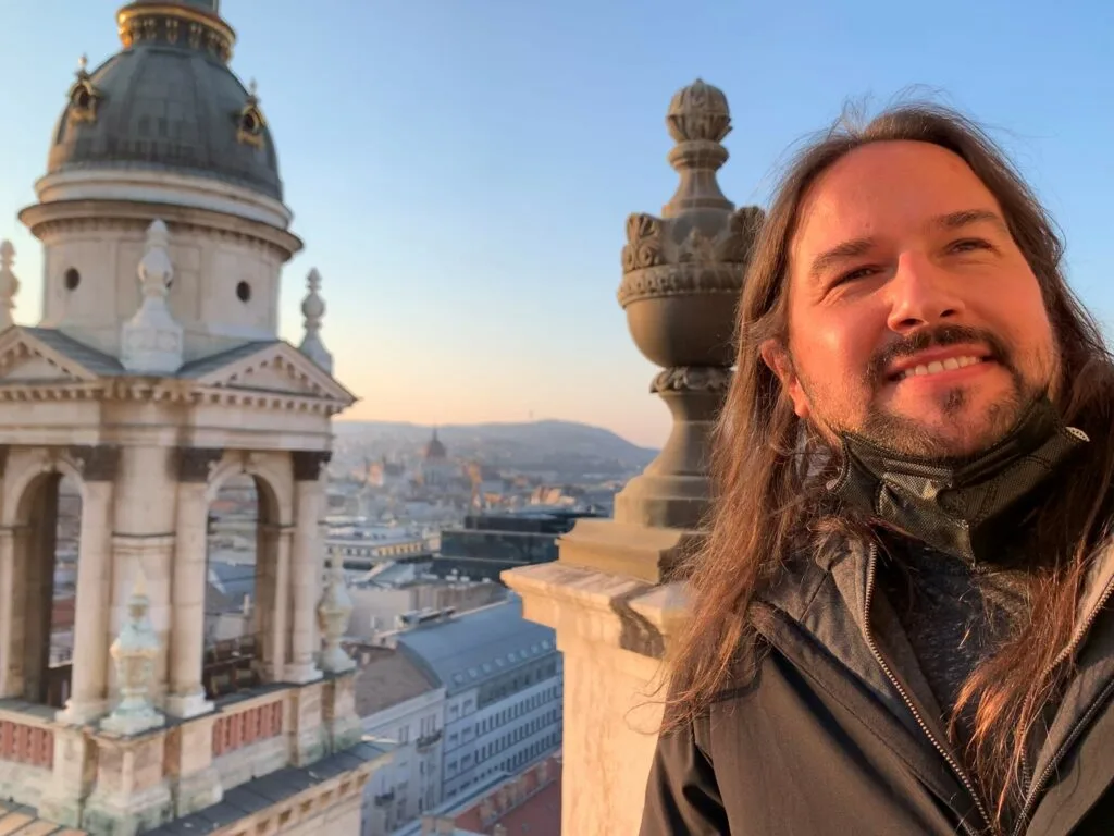Individual smiles in front of an old marble building