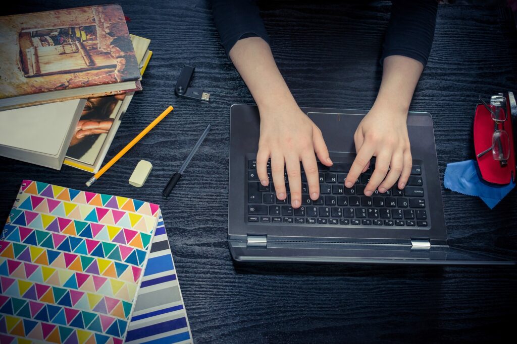 Individual on laptop with nearby school supplies