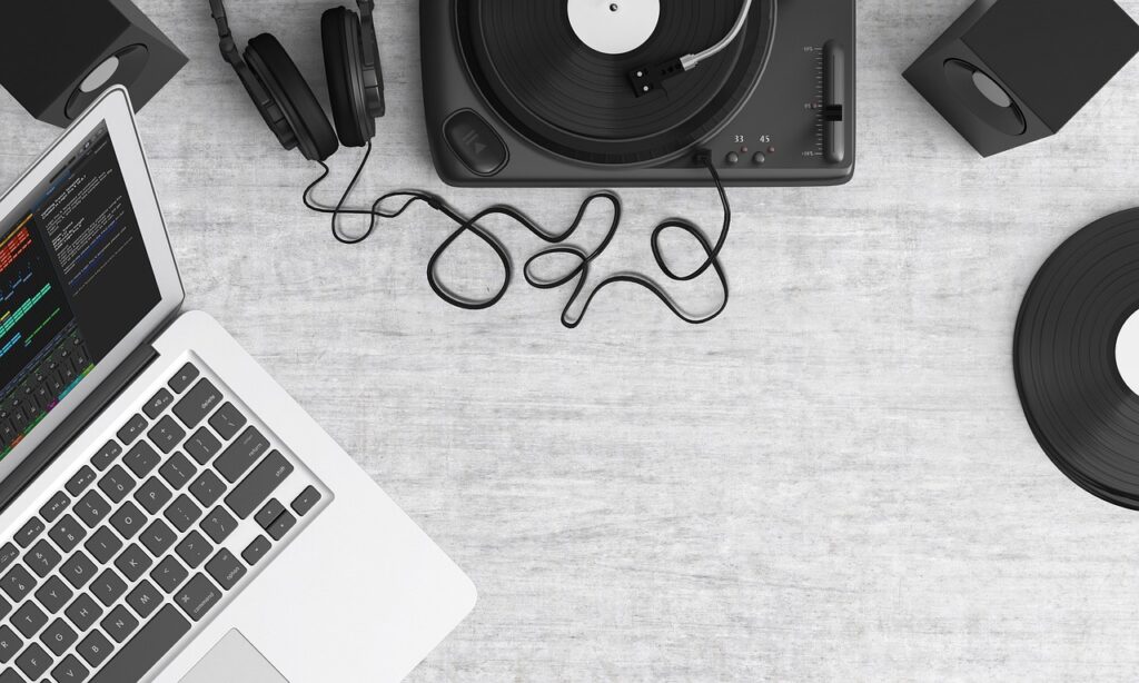 Laptop, turntable, and headphones rest on a table