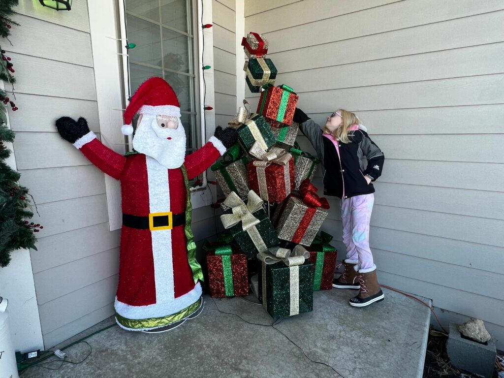 A child exploring an outdoor holiday display of stacked presents