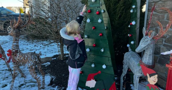 A child reaching to explore an ornament on an outdoor holiday display