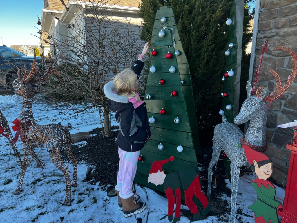 A child reaching to explore an ornament on an outdoor holiday display