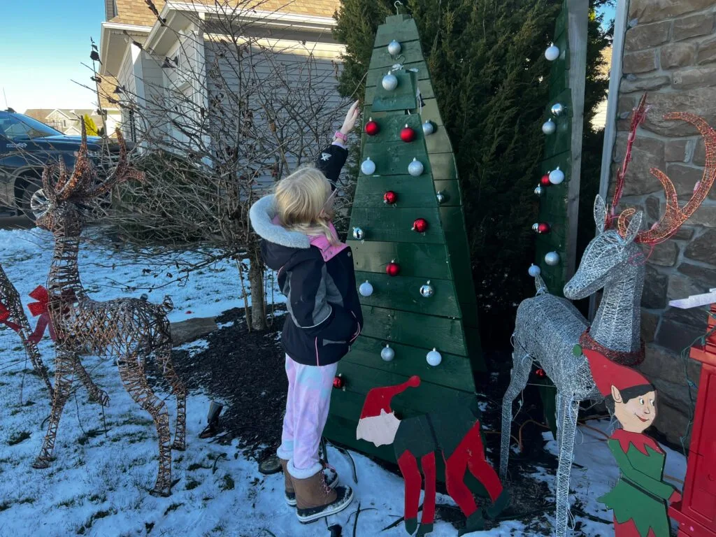 Child reaching to explore an ornament on an outdoor holiday display 