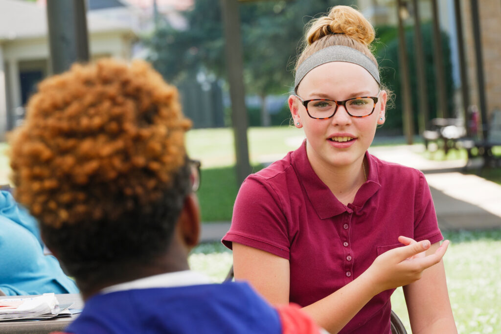 Two teens facing each other talking.