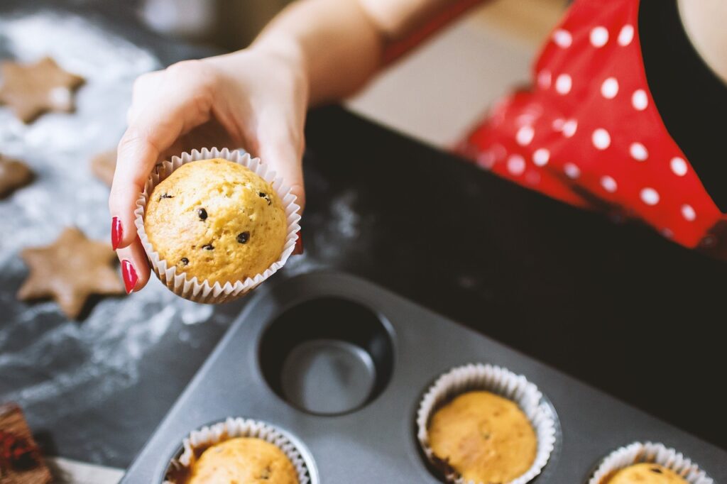 baker removing a muffin from a muffin tin.