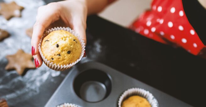 baker removing a muffin from a muffin tin.